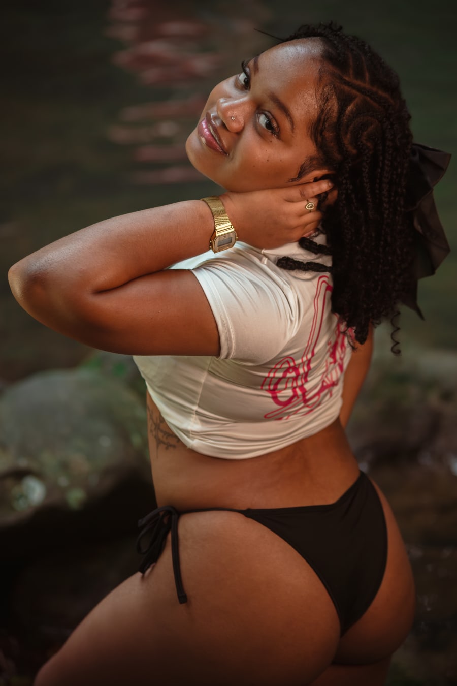 Photographie : Loana assise au bord de la cascade, en t-shirt NTL blanc