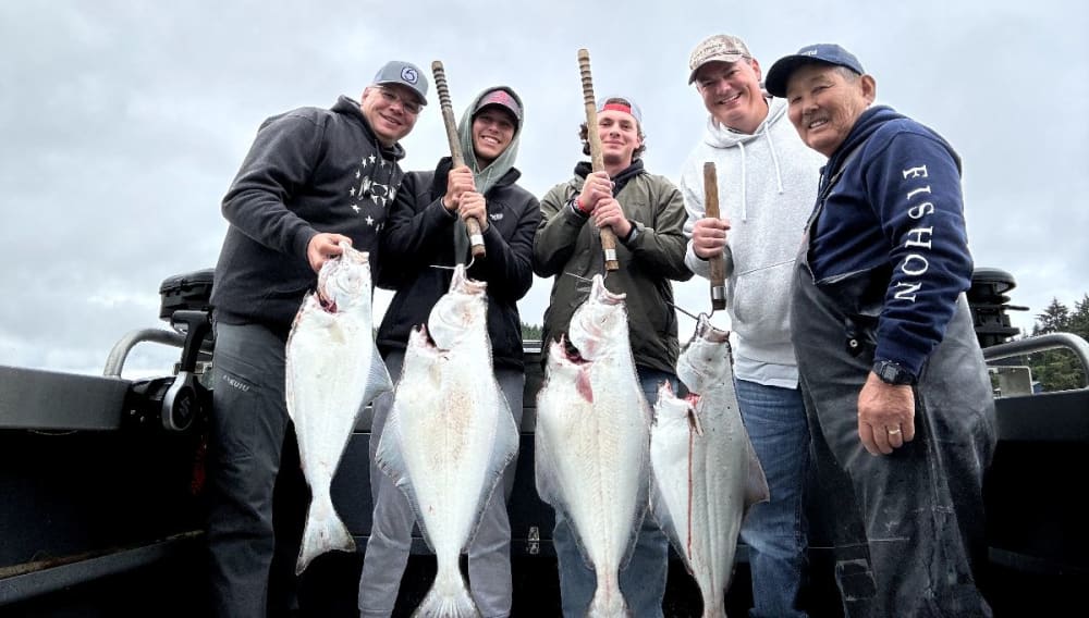 Five anglers holding up halibut on gaffs