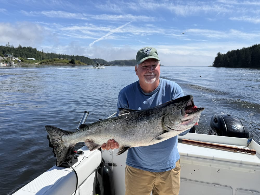 Angler holding a big Chinook salmon under blue sky