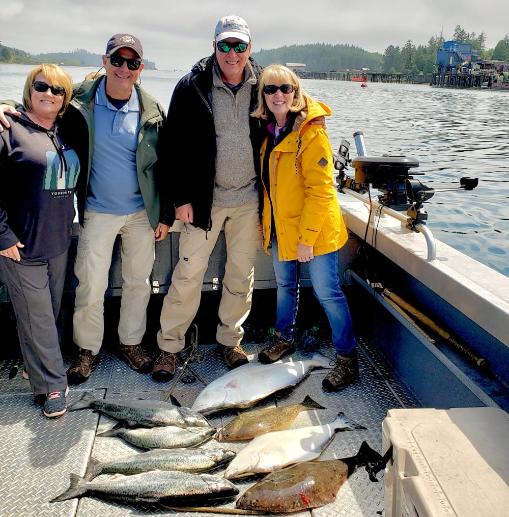Two couples on the boat with salmon and halibut