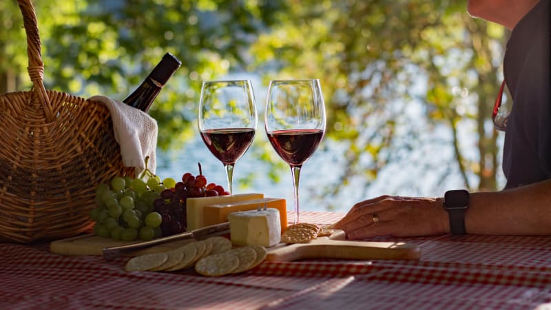 Wine, cheese and grapes on a table by the water