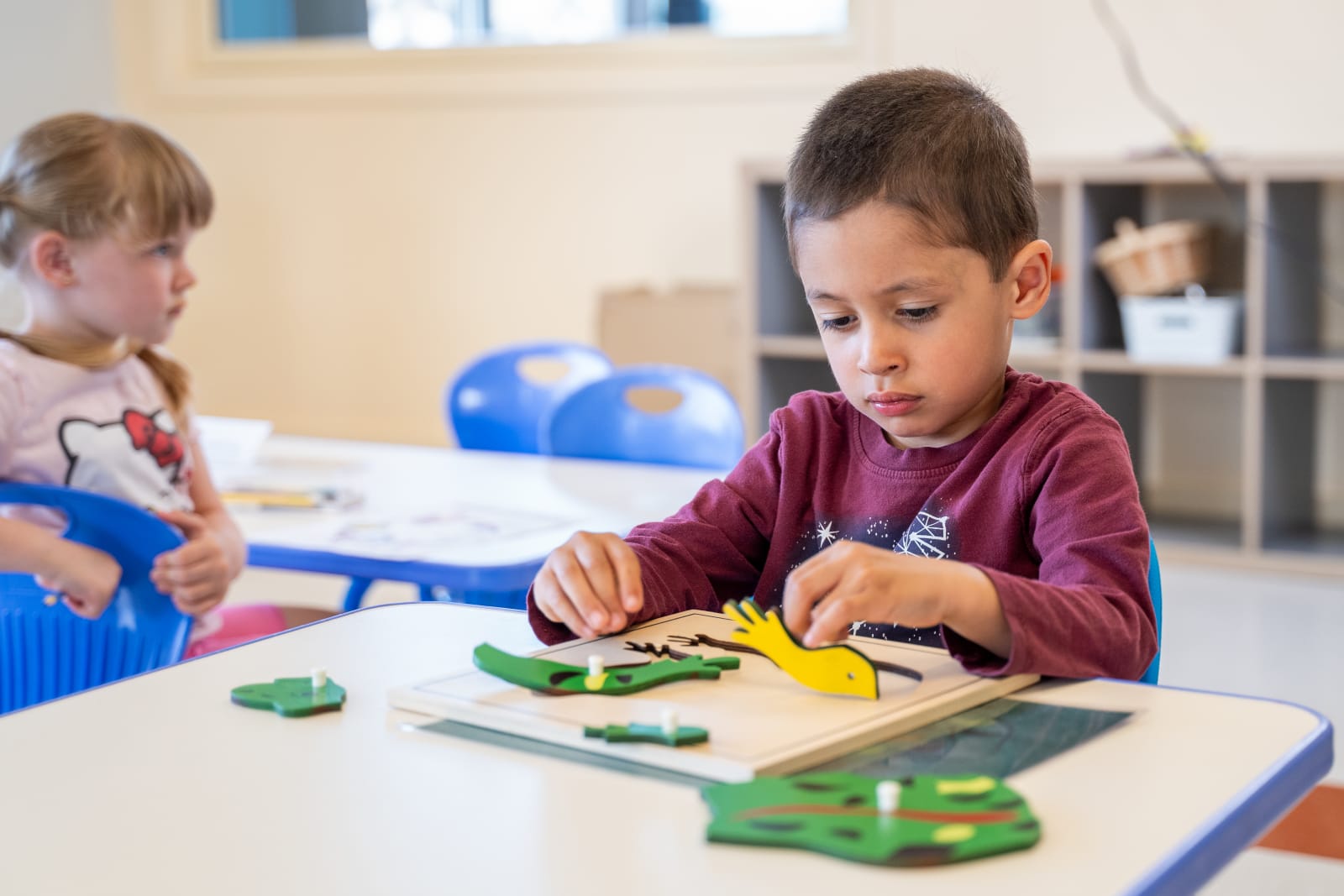 Garderie Ami Câlin : activité de motricité fine à table, où un enfant assemble des pièces pédagogiques pour stimuler la concentration et la logique.