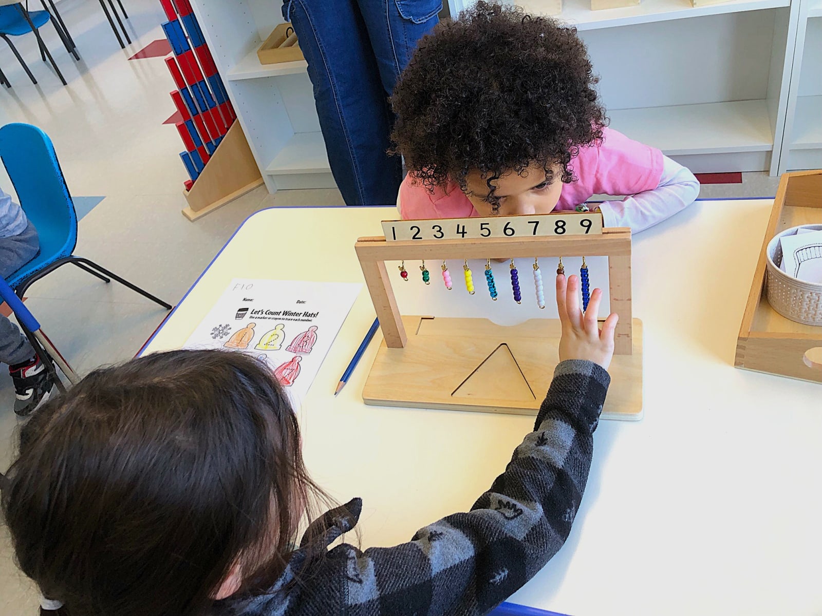Garderie Ami Câlin — activité de mathématiques Montessori : des enfants utilisent un support de perles colorées pour compter de 1 à 9 et construire la logique mathématique par la manipulation sensorielle. Inscriptions en cours à Gatineau. — Garderie Ami Câlin — Exercice Montessori de comptage avec perles — Mots-clés : Garderie Ami Câlin, mathématiques Montessori, comptage en petite enfance, inscriptions, environnement éducatif réel.