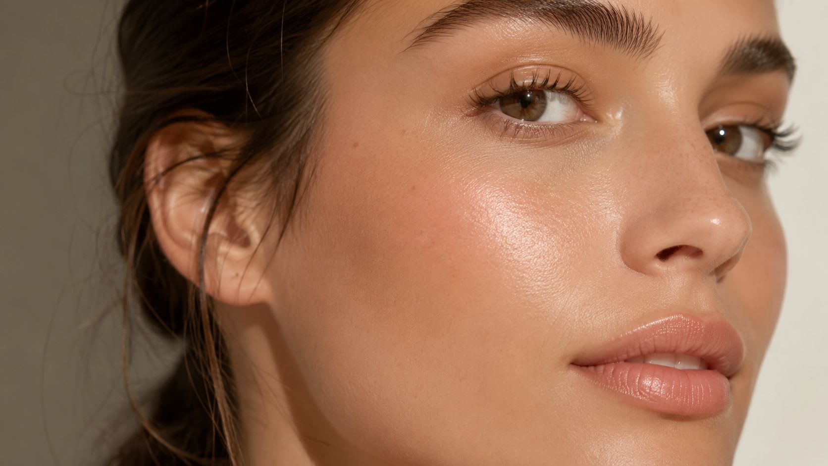 A close-up portrait of a woman with glowing, radiant, and healthy skin showing natural facial features.