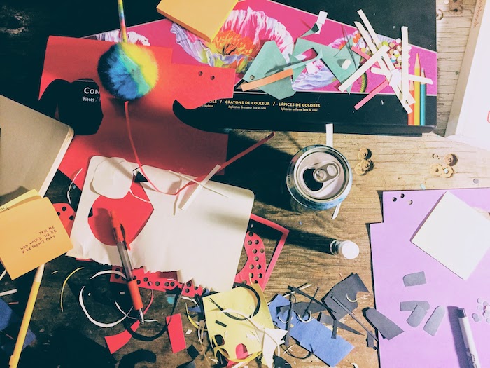 flat lay of a creative workspace with paper scraps, pencils and pens, and sticky notes