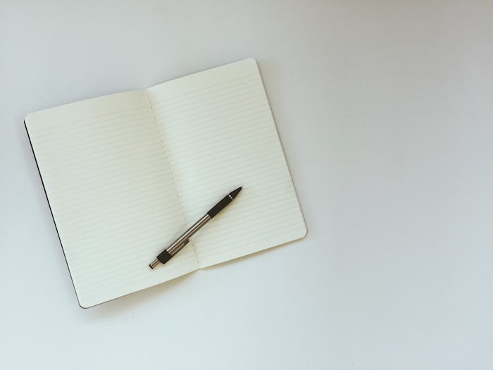 flat lay of a lined notebook and black pen on white background