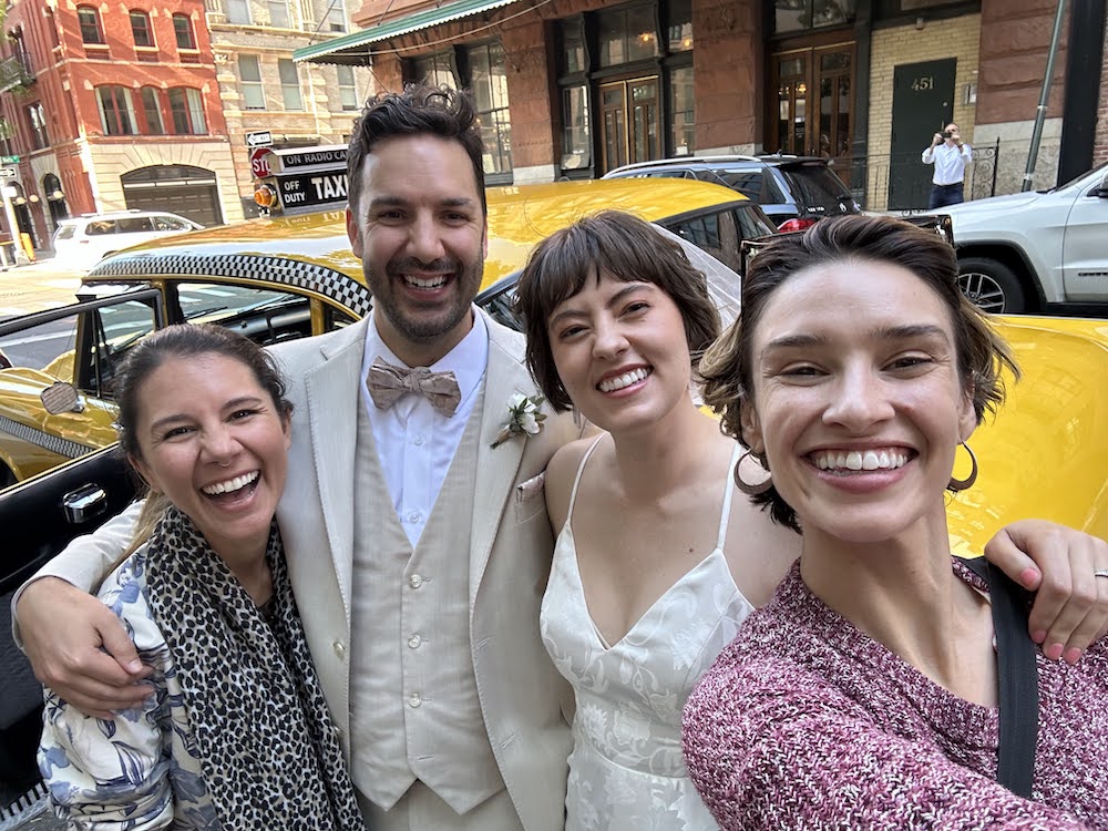 selfie of me, my husband, my cousin, and my sister-in-law in front of a vintage yellow cab