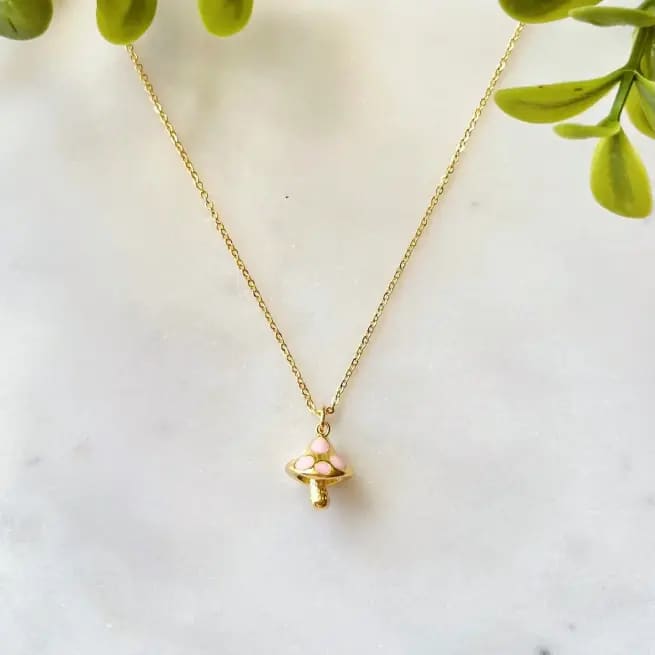 Gold chain necklace with a gold and pink mushroom charm.