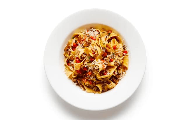 A plate of pasta ai funghi with chestnut mushrooms, topped with parmesan.