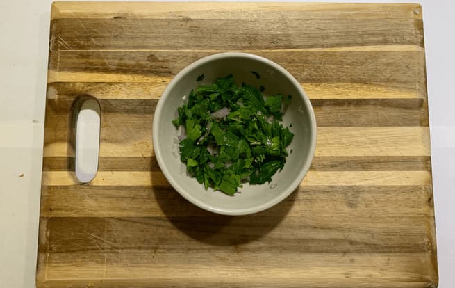 A mixture of shallots, parsley, and rice vinegar on a cutting board.