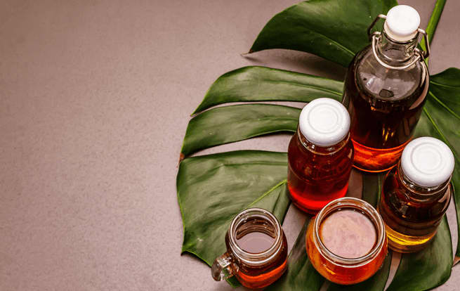 Bottles of kombucha sitting on a large leaf.