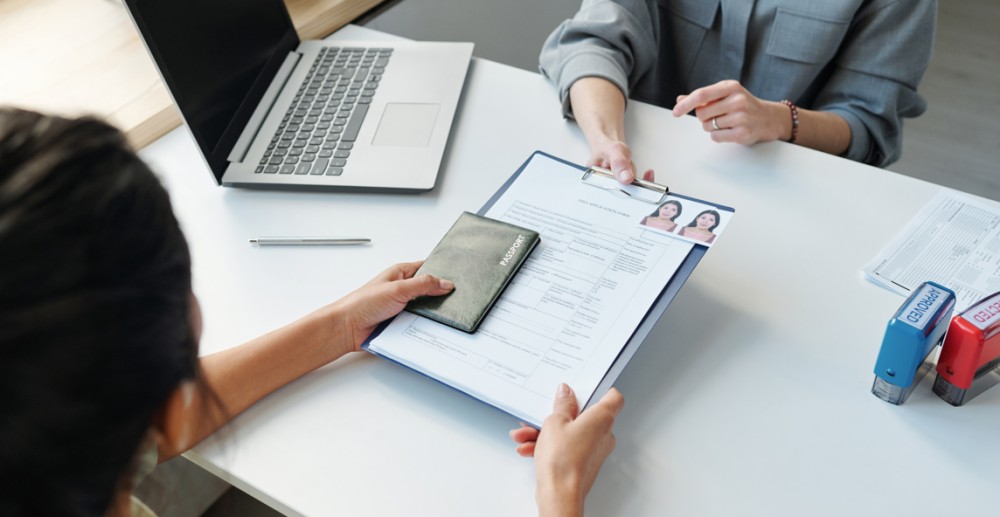 woman submitting visa documents for residency on table