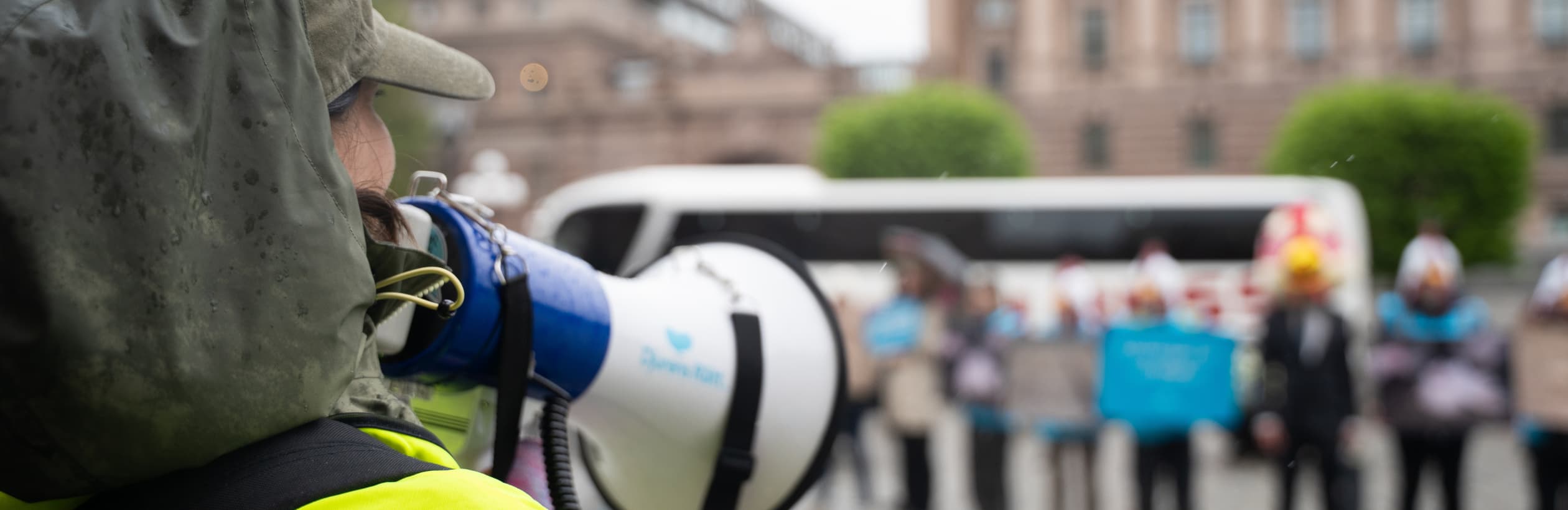 Person som talar i megafon under manifestation på Mynttorget