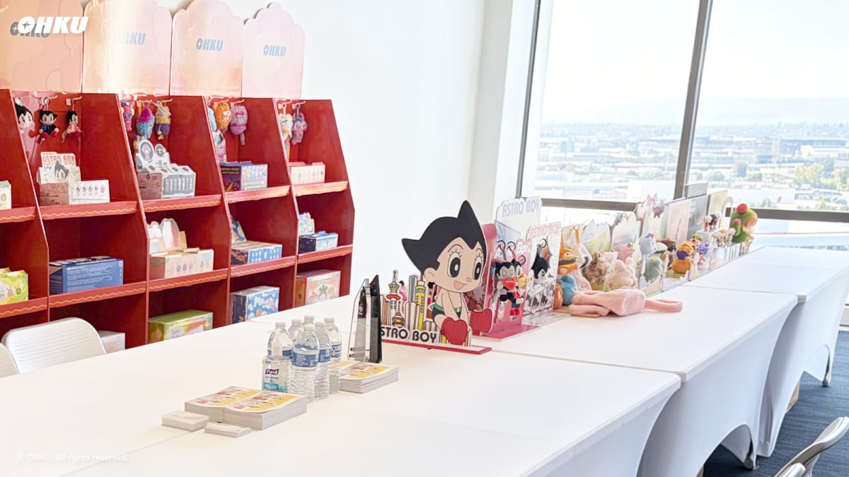 Astro Boy collectibles, plush toys, and merchandise showcased in a meeting room with large windows overlooking a cityscape