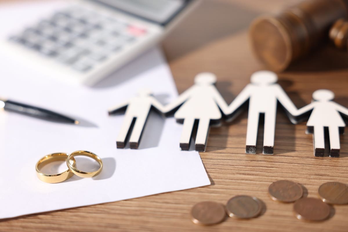 Wedding rings, a paper family cutout, and a gavel symbolizing divorce and family law in Monmouth County, NJ