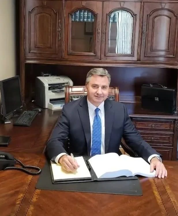 Craig A. Fahey, San Diego disability attorney, seated at his office desk in a navy suit, reviewing legal documents.