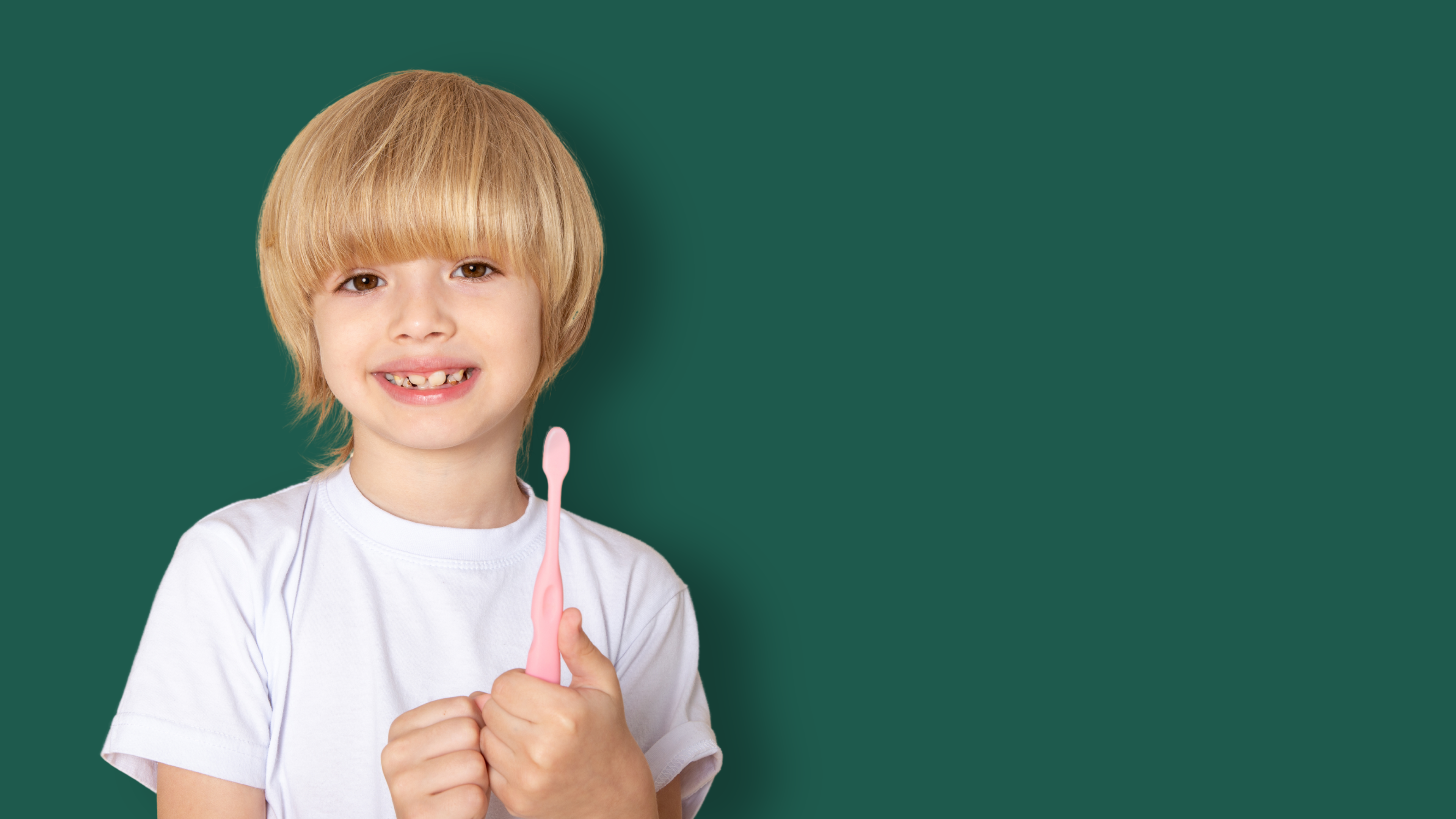 A young boy smiling while brushing a large tooth model with a toothbrush.