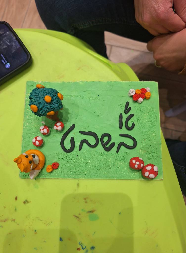 תקריב של יצירת פלסטלינה צבעונית ומורכבת המציגה דמות חייזר ירוק עם עין אחת גדולה.