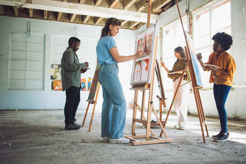 Youth artists painting at easels in a sunlit studio