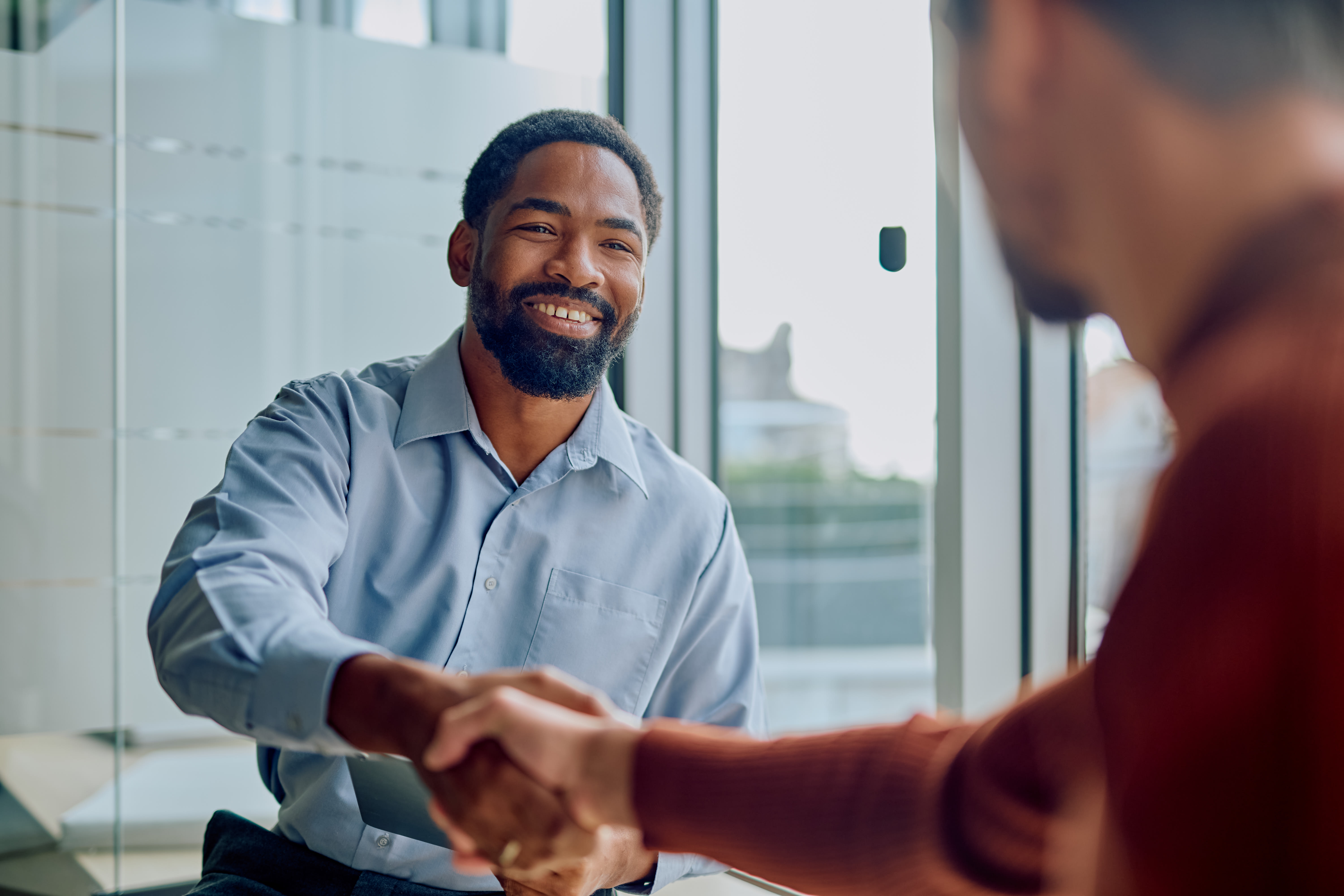 Businessmen shaking hands and smiling during a meeting celebrating a successful deal and new professional partnership