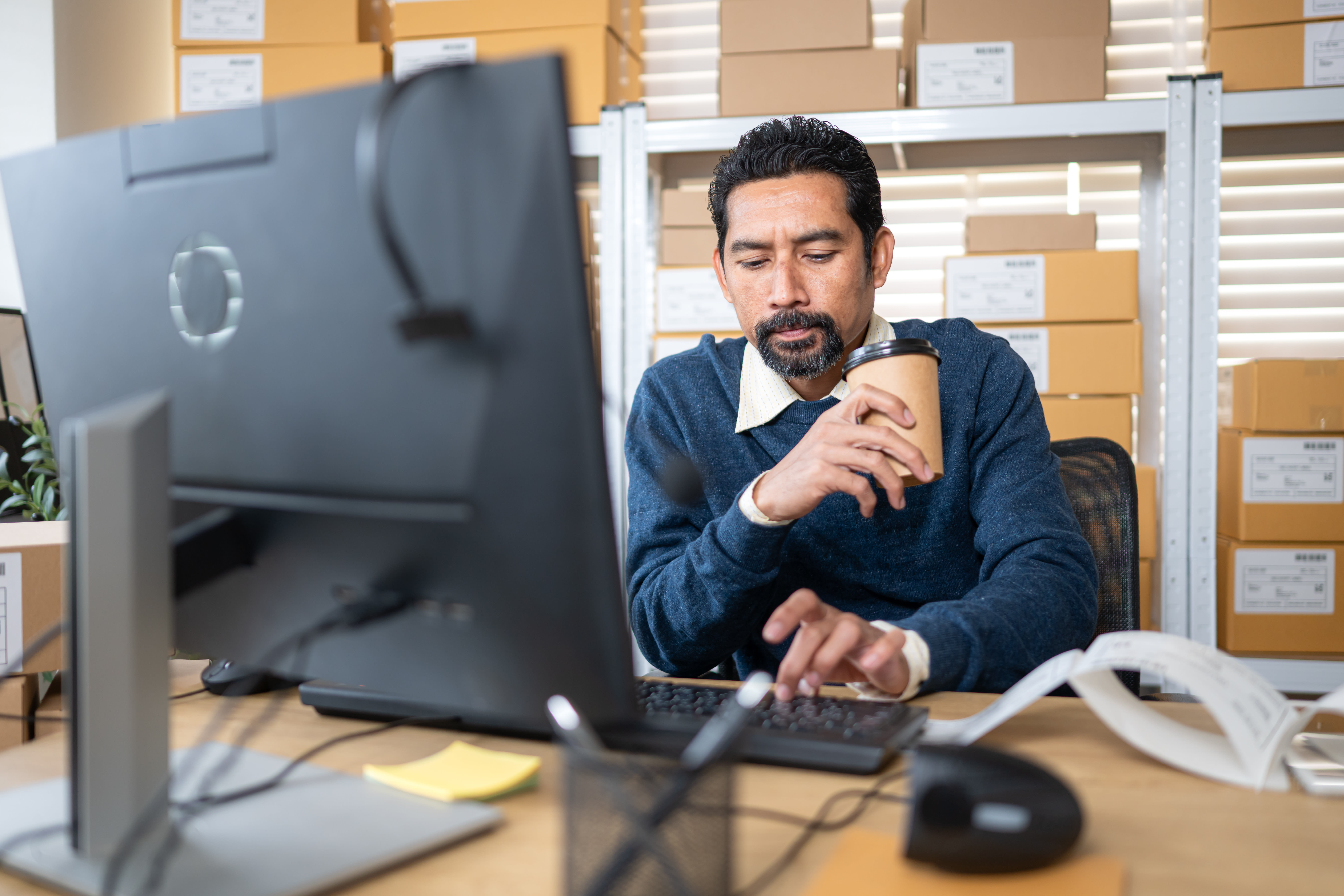 Small business owner using HookedGrowth at warehouse office and drinking coffee 