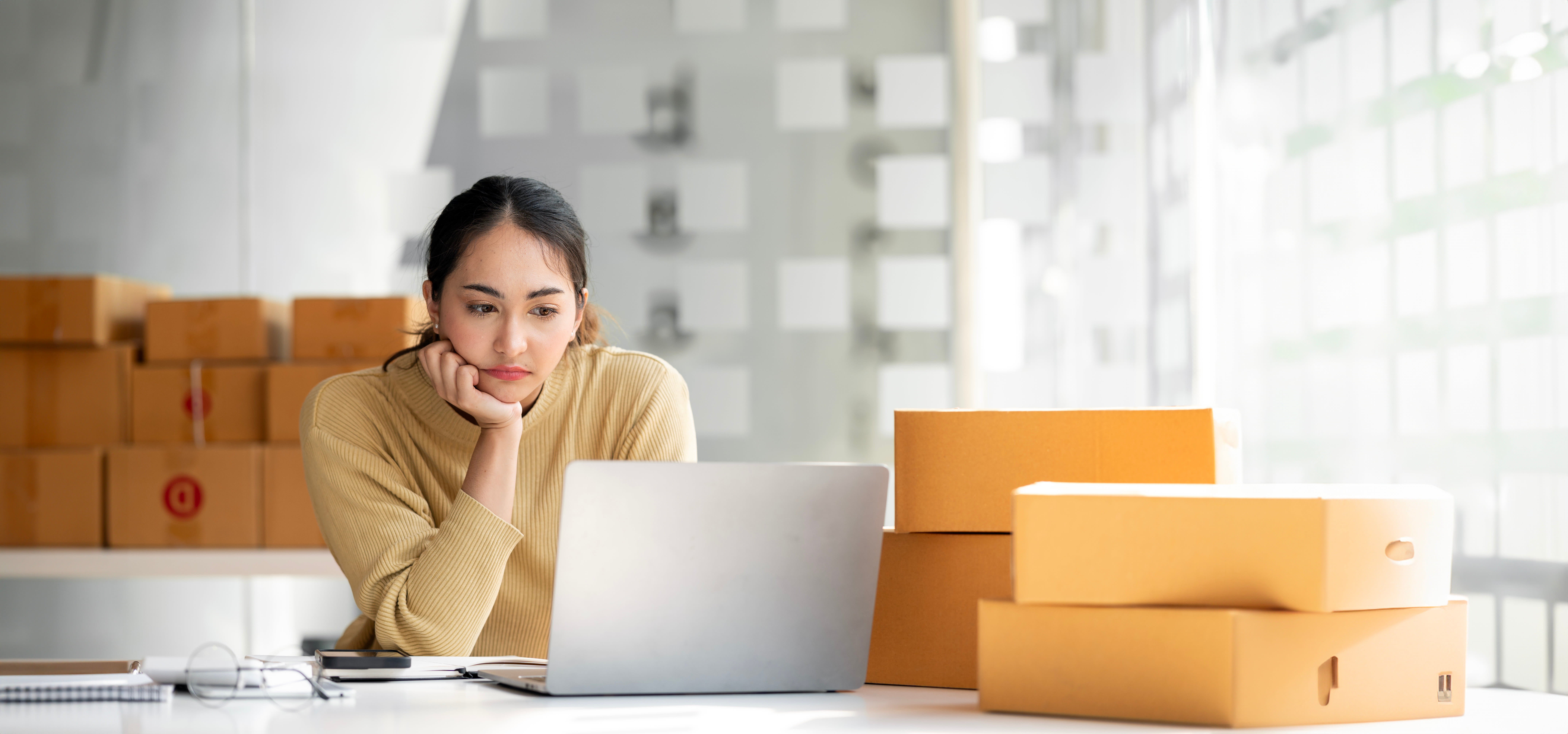 Woman looking at the laptop with a quiet expression, focused and a bit lost