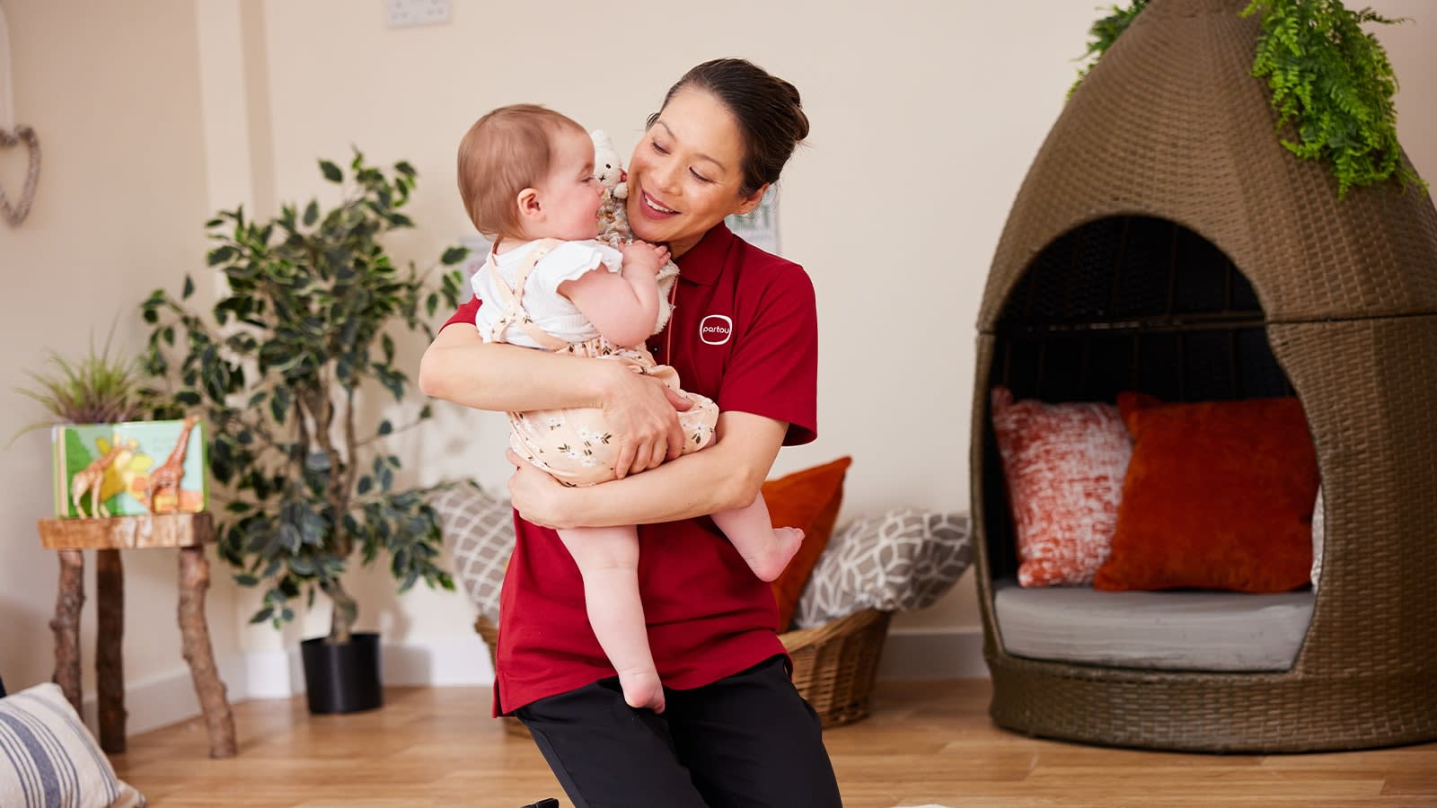 Female nursery worker holding a young baby