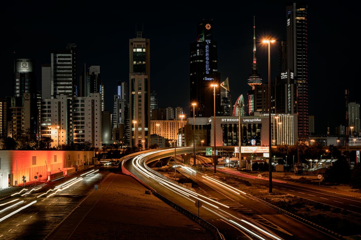 Nighttime cityscape showcasing Kuwait City's illuminated skyline and bustling streets.
