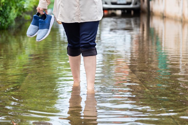 Woman,Walking,On,Flooding,Road,With,Holding,Shoes,After,The