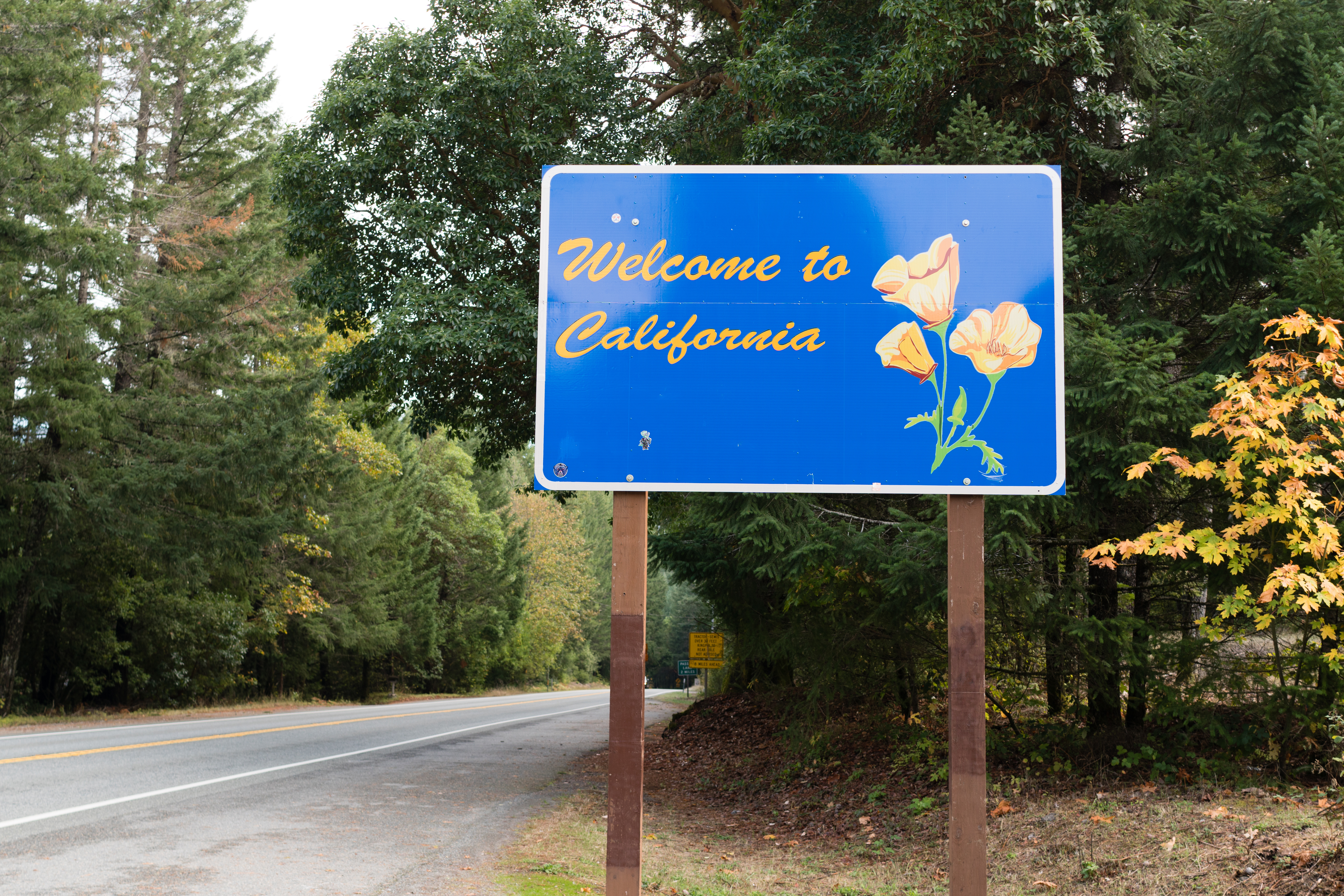 Welcome to California state sign — relocating buyers crossing into California face higher and more variable closing costs than Oregon, including county and city-level transfer taxes.