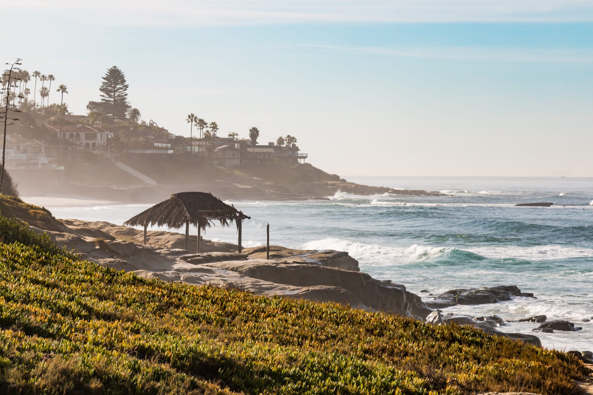 Homes along La Jolla Shores beach with waves rolling in