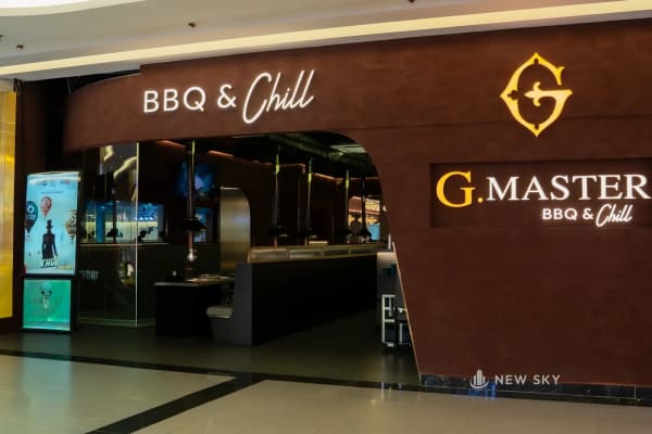 Mặt tiền G.Master tại tầng B1 Landmark 81: mảng tường trát nâu đỏ khoét cổng vòm cong, chữ nổi BBQ & Chill phía trên và biển G.Master gắn bên phải.