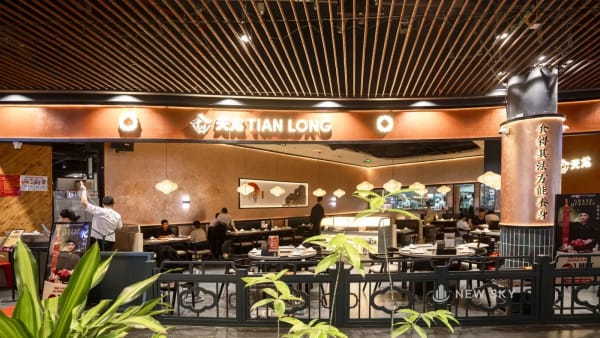 Toàn cảnh gian Tian Long mở ra hành lang Aeon Hải Phòng, lan can thấp hoa văn mây làm ranh giới, cột ốp đồng khắc chữ Hán.