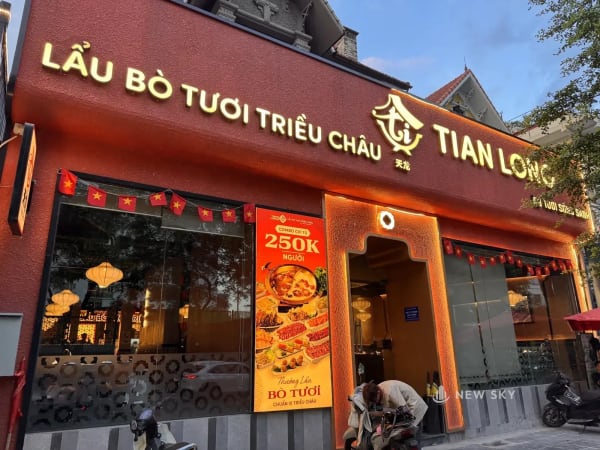 Mặt trước nhà hàng Tian Long trên đường Nguyễn Phan Chánh: tầng trệt là kính suốt, bên trên chạy dải biển màu đỏ sẫm nghiêng ra ngoài với dòng chữ vàng khổ lớn, trước cửa là xe máy dựng trên vỉa hè.