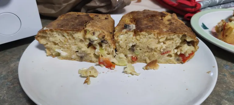 Unbaked Serbian Carska Pita batter in silicone baking molds with visible vegetables and feta cheese before baking