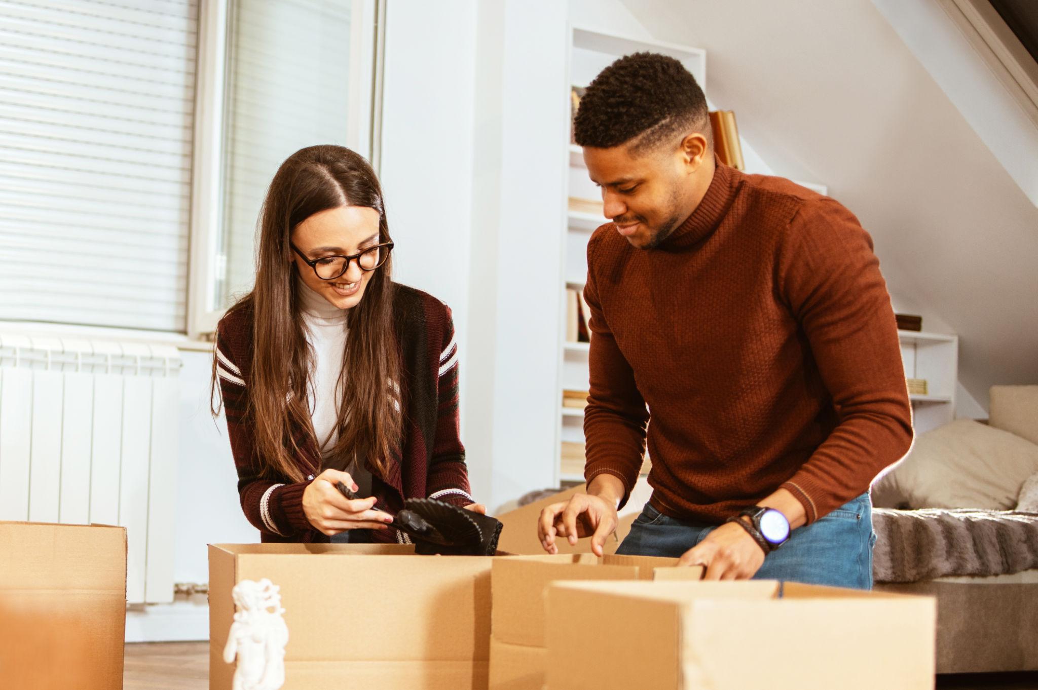 Umzugshelfer beim sorgfältigen Packen eines Kartons in einer hellen Altbauwohnung