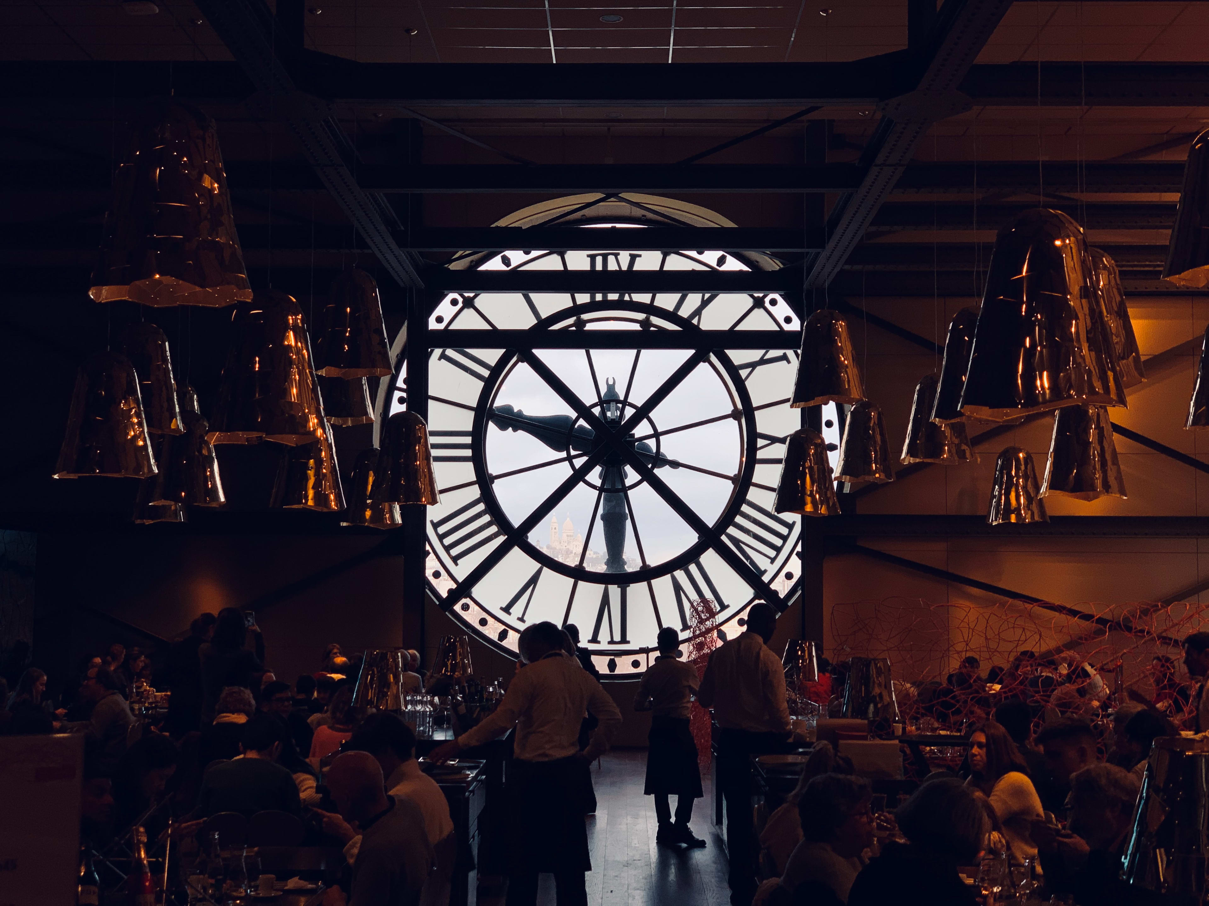 Photograph of the inside of a restaurant at Musée d'Orsay in Paris. The restaurant contains a large window through the building's clockface.