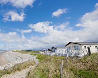 A sunny, cloudy day overlooking the beach at Barmouth Bay, North Wales. Book now to stay in one of our luxury static caravans. image