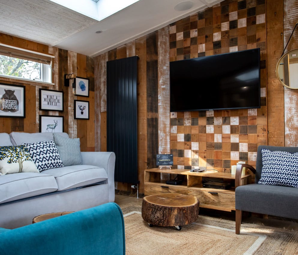The lounge area in The Knightwood holiday lodge. This lodge has large sofas, a flatscreen TV, and plenty of rustic, woodland décor to enjoy.