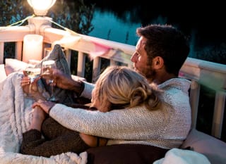 A couple sitting outside their holiday home with a drink of wine. image