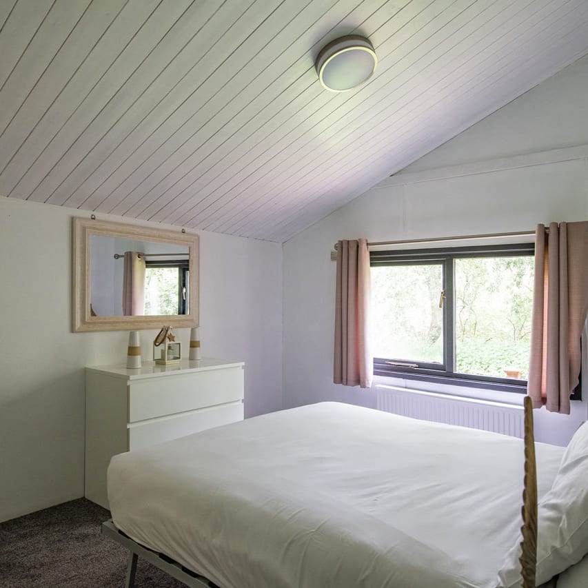 The interior of one of our Comfort holiday lodges. There's a double bedroom with a mirror and large window.