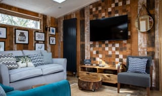 The lounge area in The Knightwood holiday lodge. This lodge has large sofas, a flatscreen TV, and plenty of rustic, woodland décor to enjoy. image
