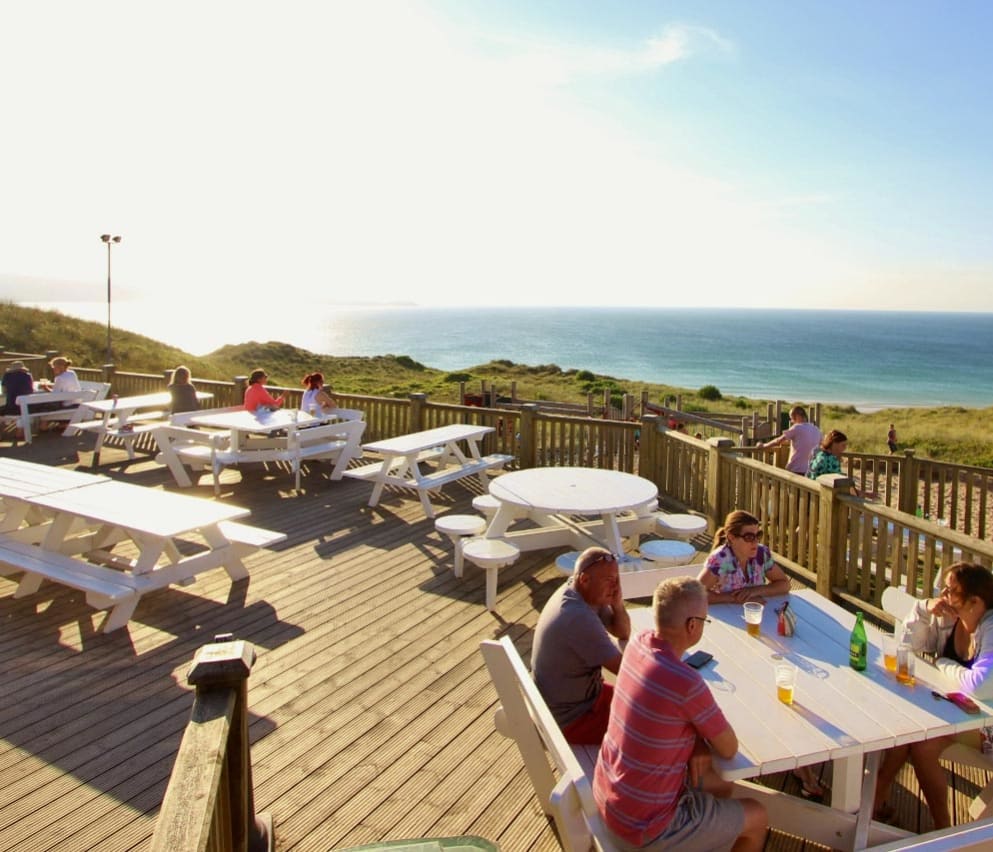 The outdoor eating area of our restaurant at St Ives Bay Holiday Park, with views of the sea.