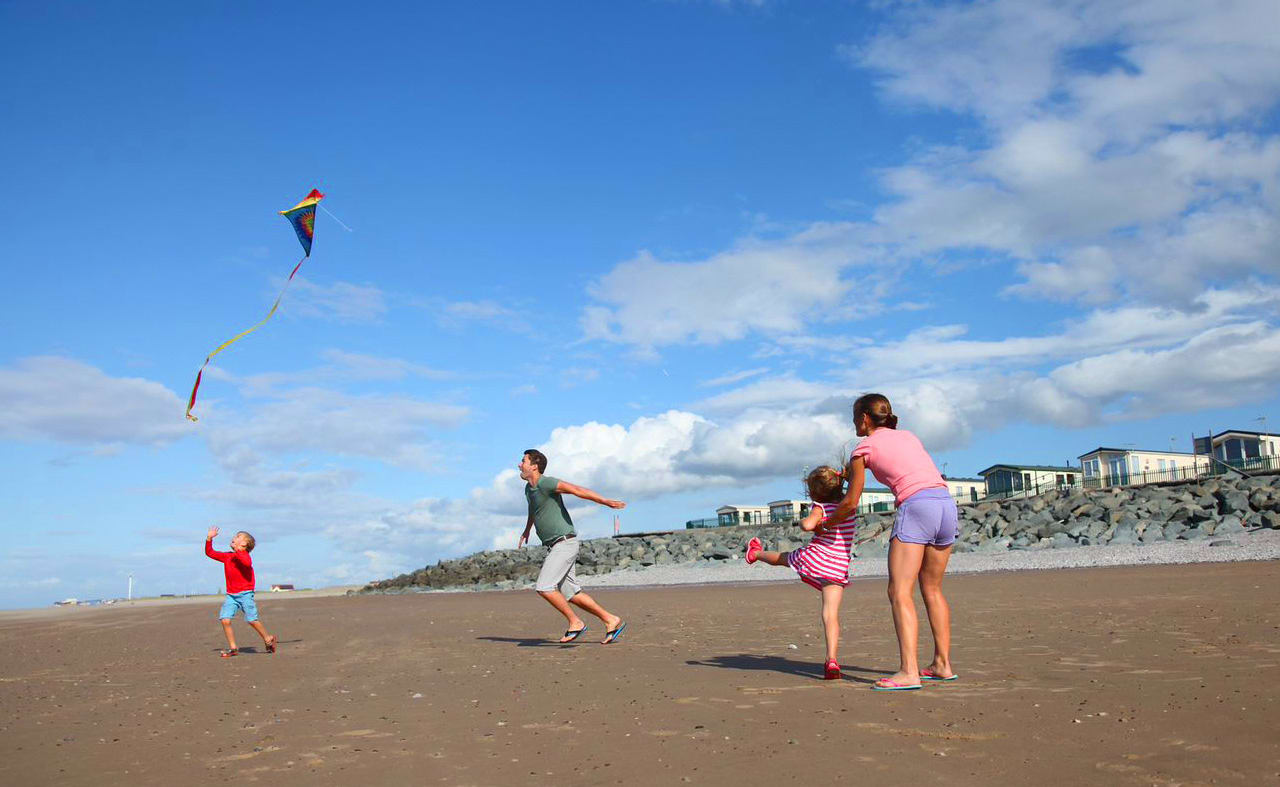 A family of four playing on the beach at our North Wales holiday park, Golden Sands. image