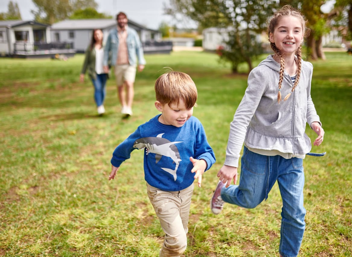 Two young children running towards the camera smiling. image