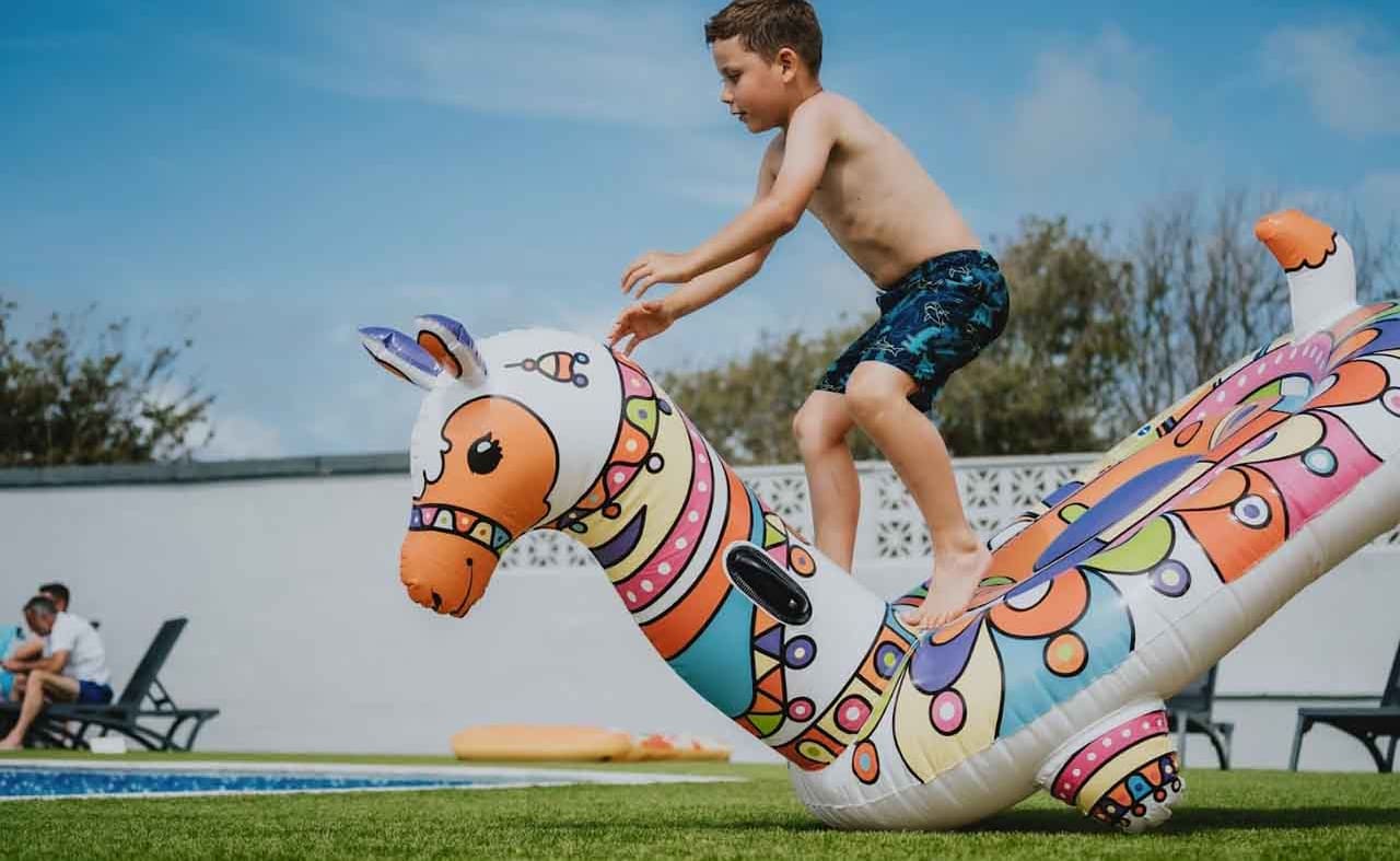 A young white boy, jumping onto an inflatable lama into the outside pool. image
