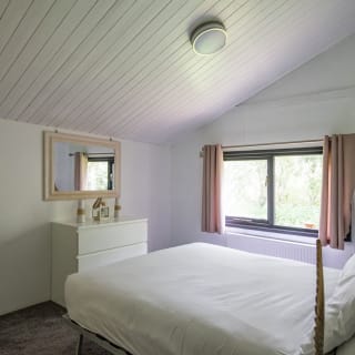 The interior of one of our Comfort holiday lodges. There's a double bedroom with a mirror and large window.