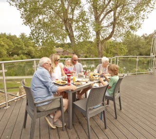 A family sat in the outdoor seating area at The Lakeside Bar & Eatery on a summers day at our park in the Isle of Wight, The Lakes Rookley. image