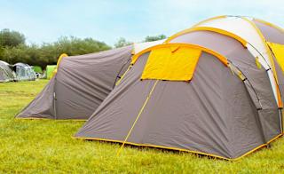 A shot of the back of two grey and yellow pitched up tent on some grass. image