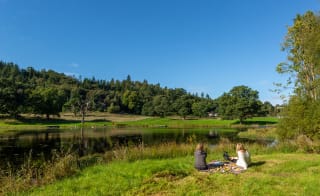 Two people enjoying a picnic on a beautiful summers day at Moffat Manor holiday park, with views of the stunning surrounding scenery. image